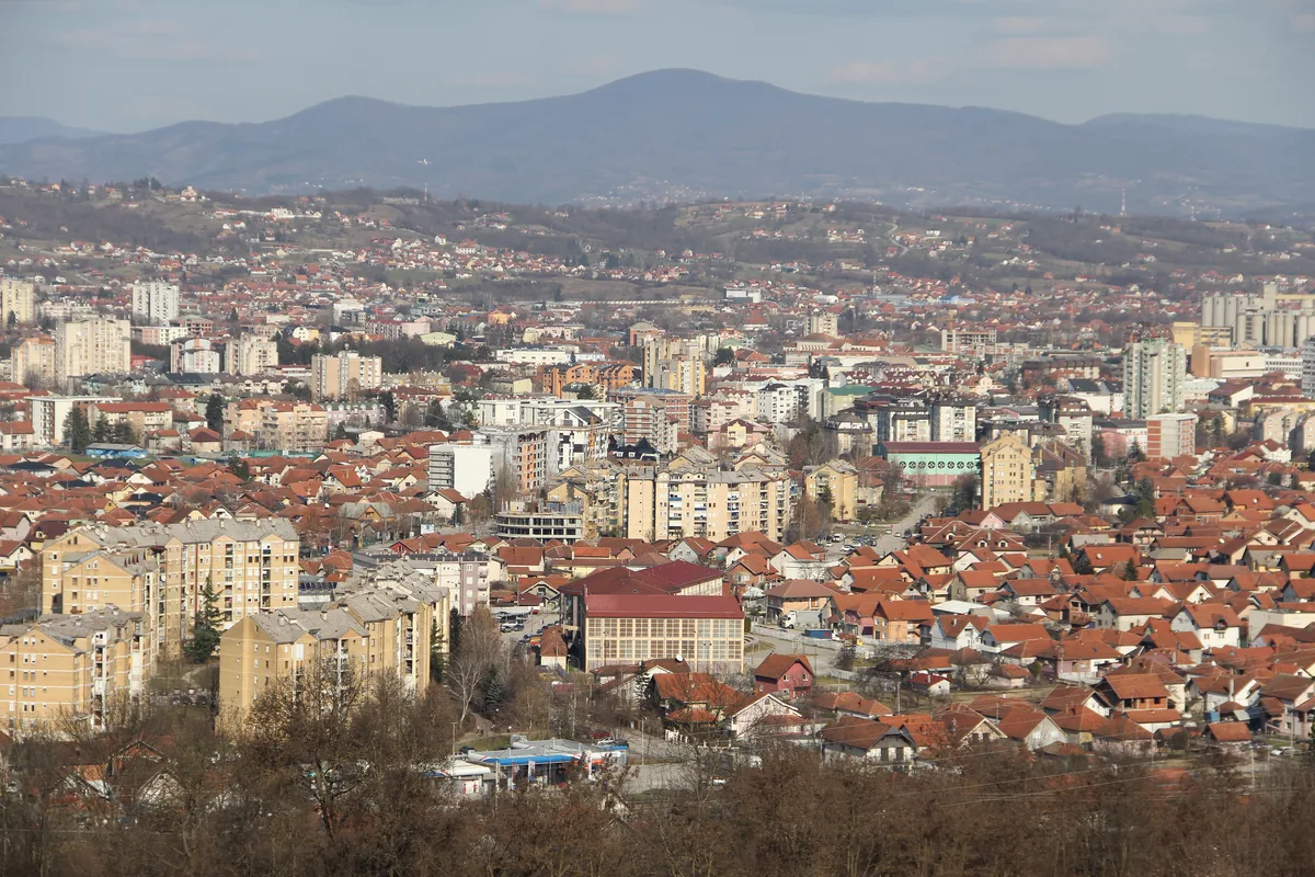 Panorama Čačka, crveni krovovi i stambene zgrade sa planinama u pozadini