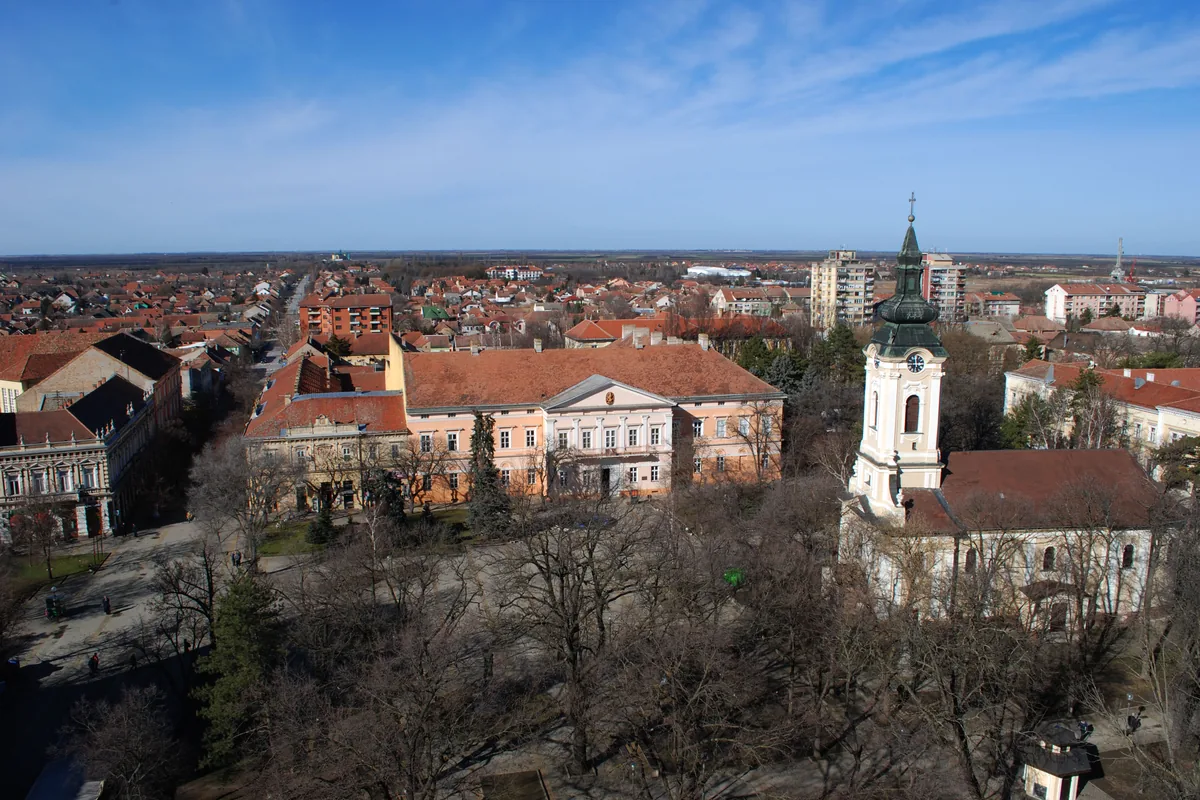 Pogled sa krova na Gradski trg u Kikindi: crkva Svetog Nikole sa zvonikom, zgrada Narodnog muzeja i ravnica na horizontu