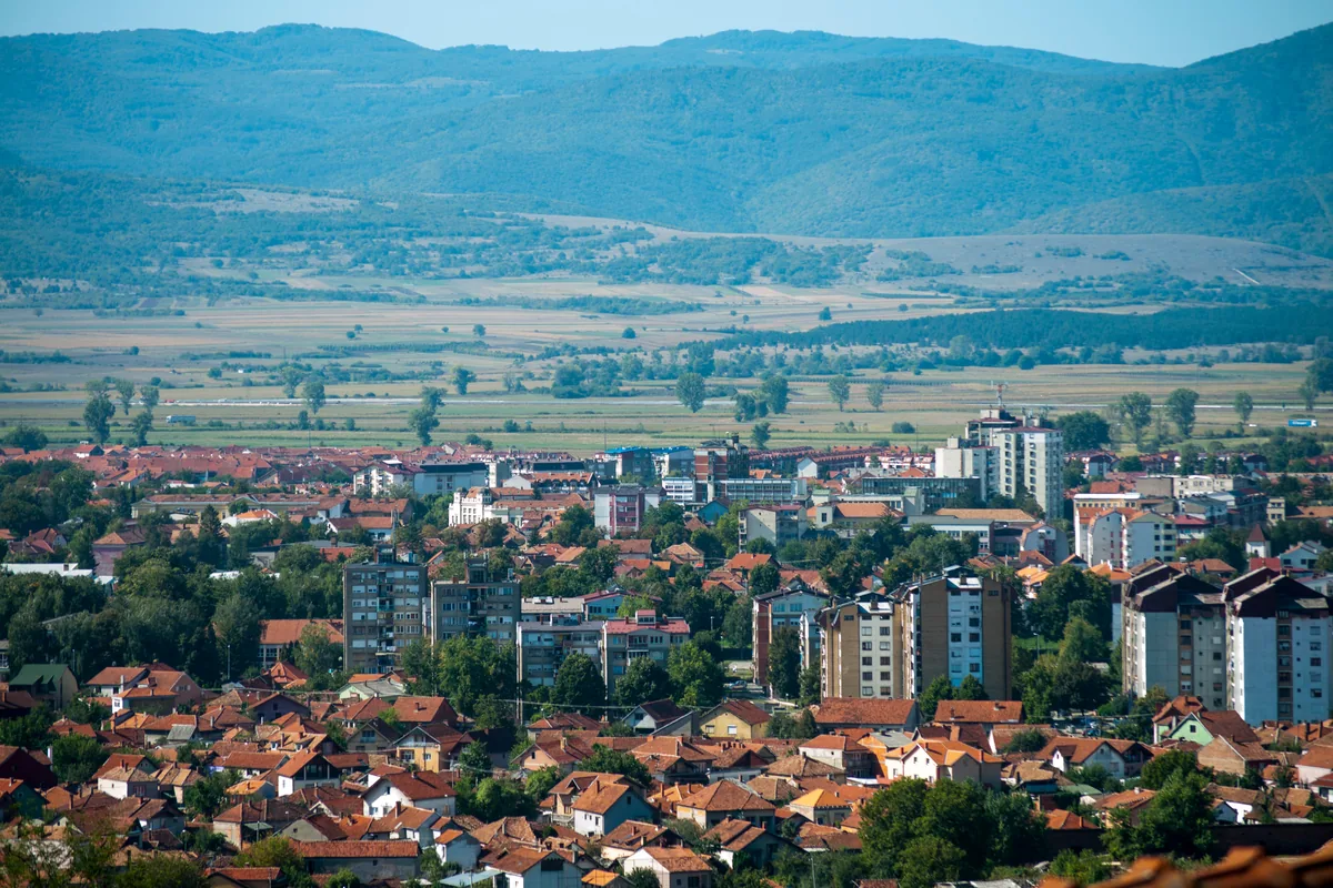 Kuće i stambene zgrade Pirota, polja u kotlini i planine u pozadini