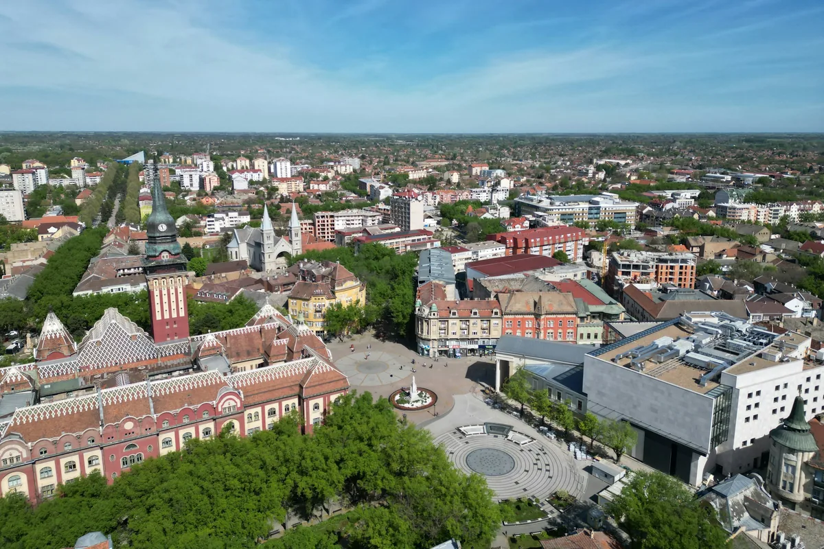 Centar Subotice iz vazduha: zgrada sa visokom kulom, trg sa fontanom i crveni krovovi do horizonta