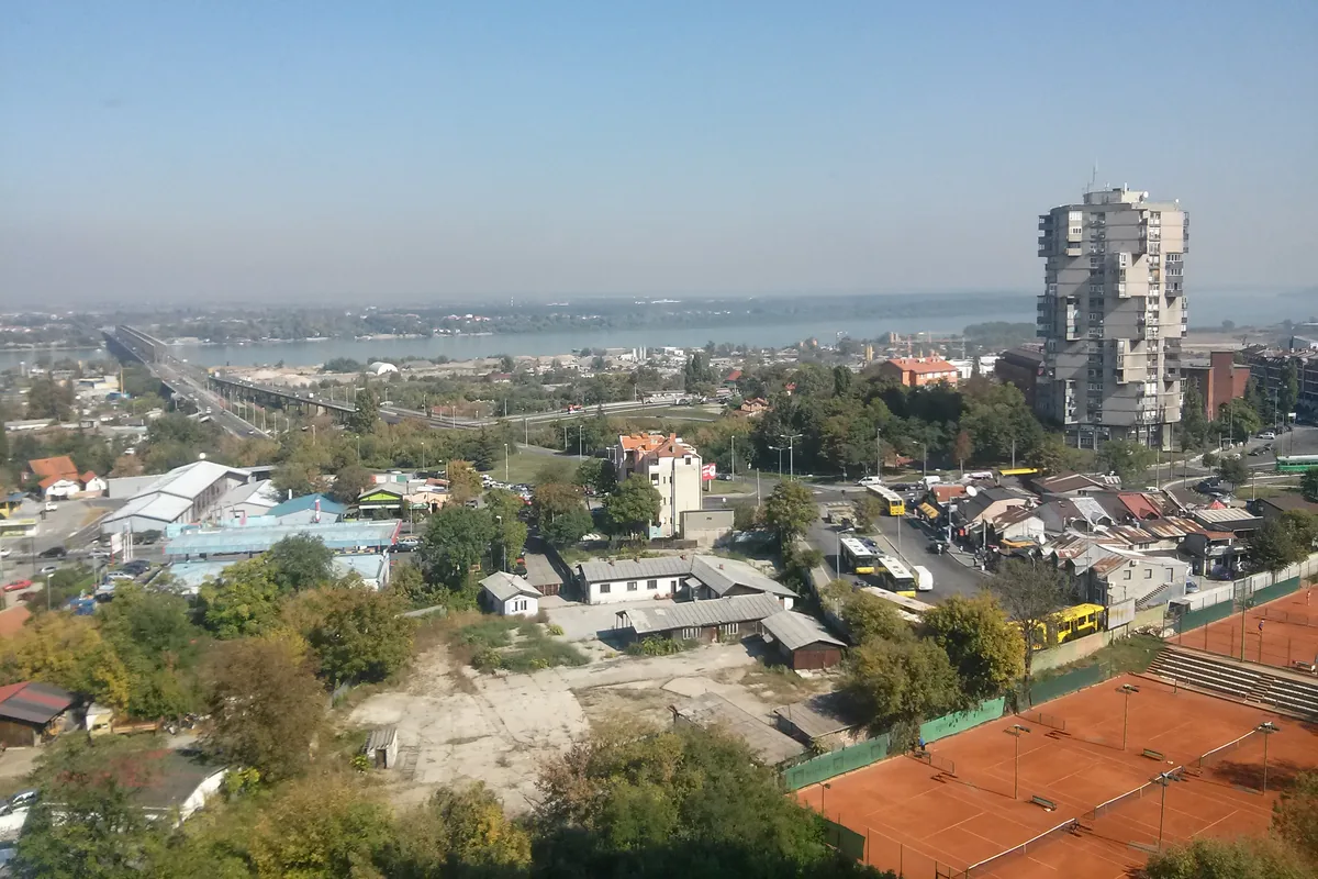 Pogled na Karaburmu sa visine: visoka stambena kula, teniski tereni, most i reka u pozadini
