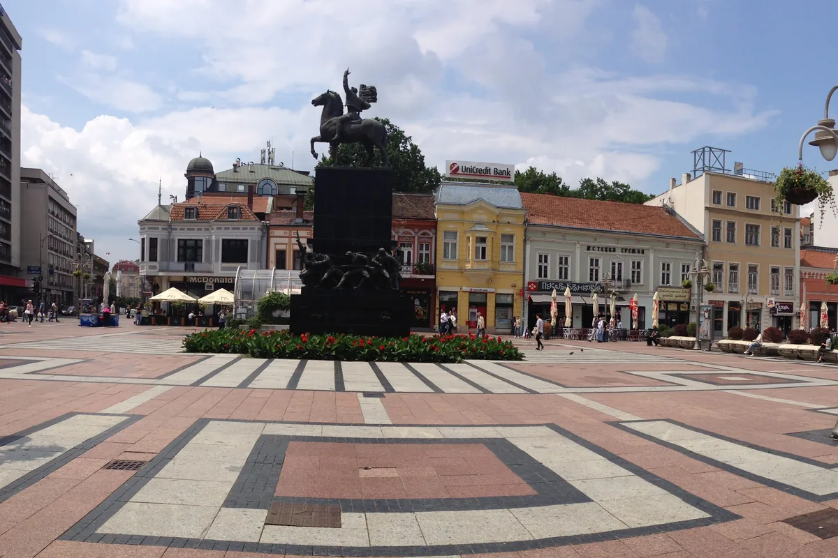 Trg kralja Milana u Nišu sa konjaničkim spomenikom, cvetnom lejom i nizom starih zgrada