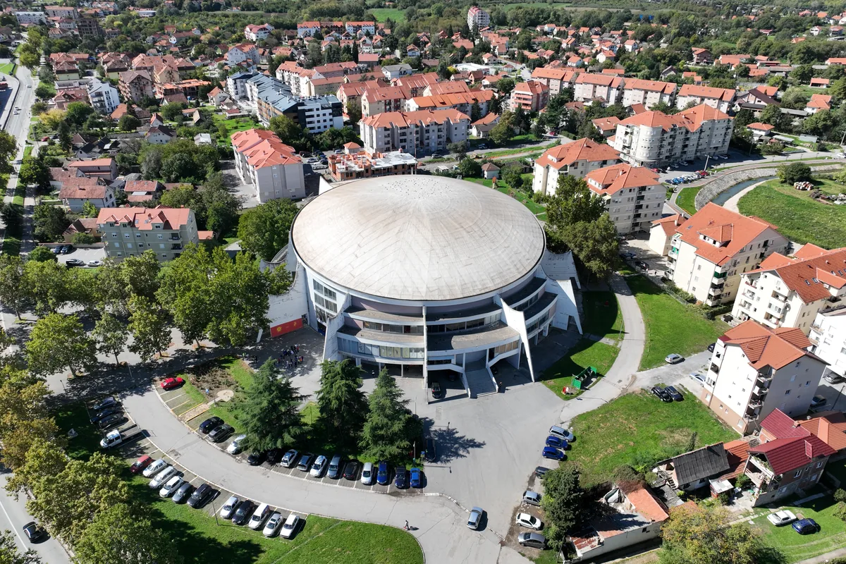 Obrenovac iz vazduha: kupolasta hala Sportsko-kulturnog centra, parking, stambene zgrade i kuće sa crvenim krovovima
