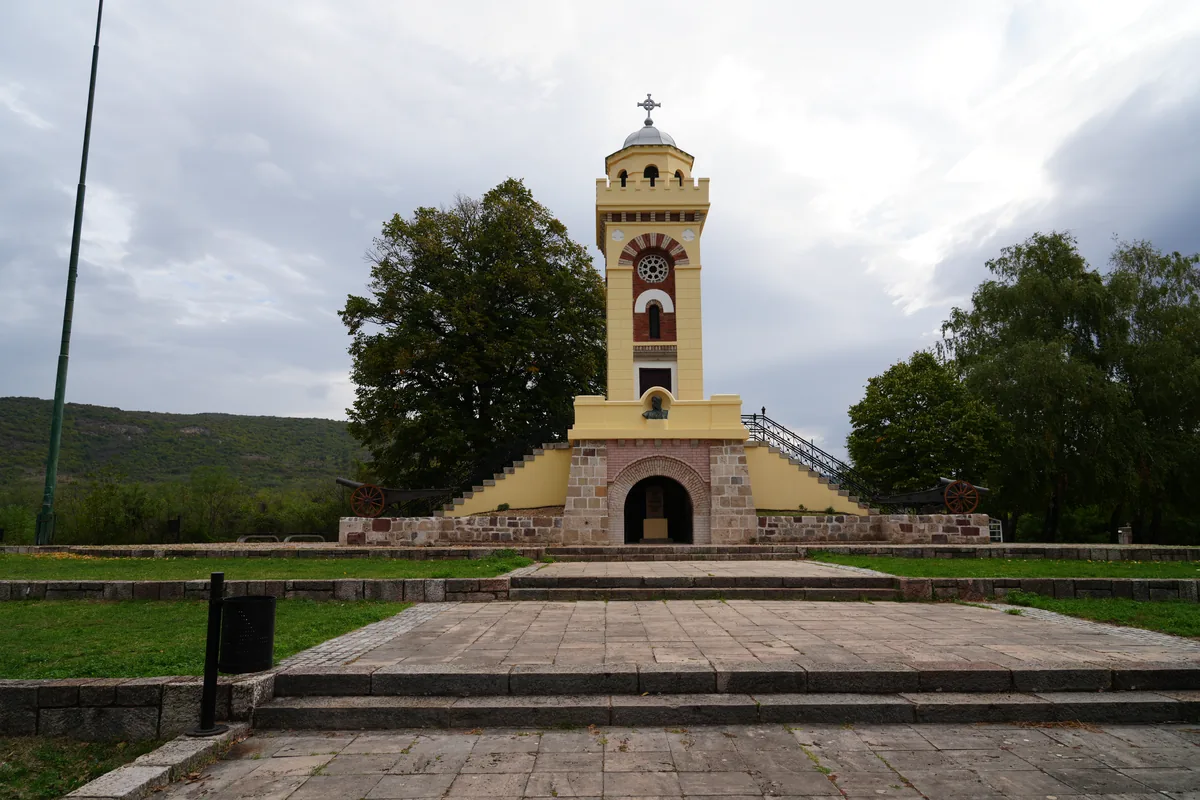 Spomen-kula na Čegru sa stepeništem, okružena drvećem pod oblačnim nebom